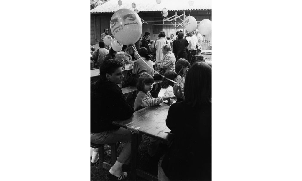 Frauenstreik im Horburg-Park, Basel: Frauen und Kinder sitzen an den Tischen im Freien. Claude Giger. Schweizerisches Sozialarchiv